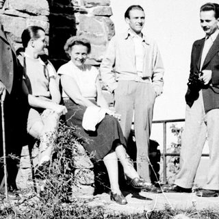 Group of four people standing near a stone wall.