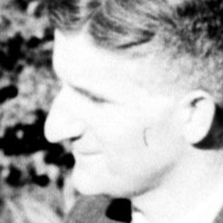Man seated outdoors, overlooking a landscape with vegetation.