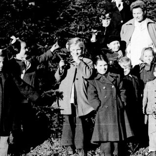 Group of children and adults pose outdoors in winter.