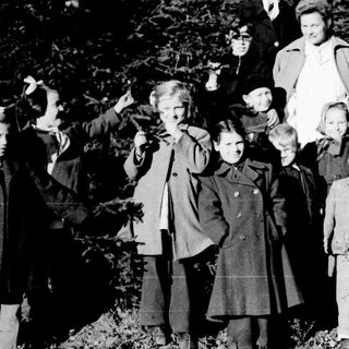Group of children and adults pose outdoors in winter.