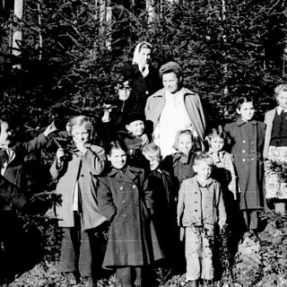 Group of children and adults pose outdoors in winter.