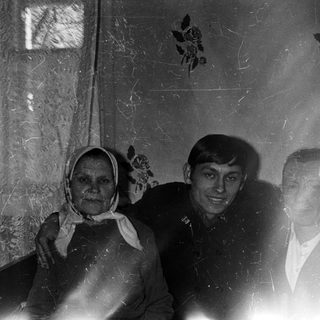 Here's a brief summary of the image: Three people posing indoors, likely a family portrait.