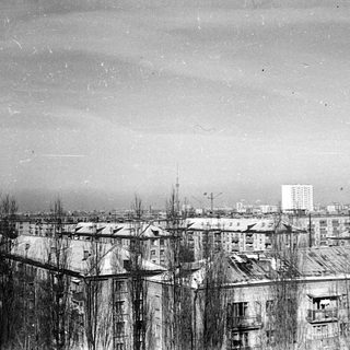 Black and white photograph depicts a cityscape with apartment buildings.