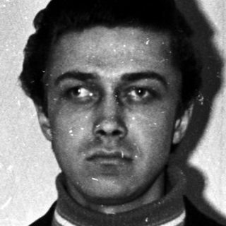 Man in suit stands facing camera in a room.