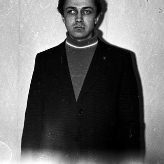 Man in suit stands facing camera in a room.