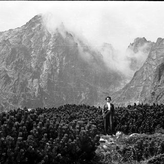 Man stands before a mountain range, shrouded in mist.