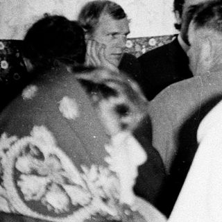 Group of formally dressed men and women in a room.