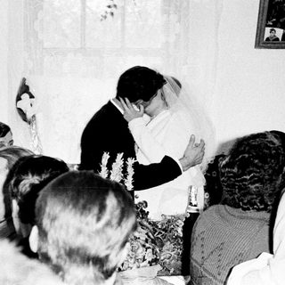 Couple kisses during a wedding reception with guests present.