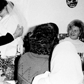 Couple kisses during a wedding reception with guests present.