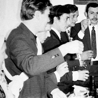 Group of men and a woman toasting with drinks.