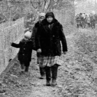 People walking along a muddy road on a foggy day.