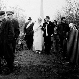 Couple walks with group near a Soviet monument.