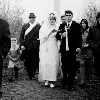 Couple walks with group near a Soviet monument.
