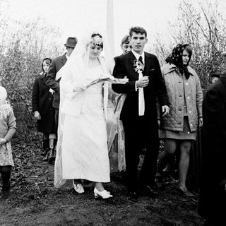 Couple in wedding attire near a Soviet-era monument.