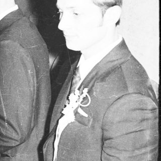 Men in suits and a woman stand in a dark room.