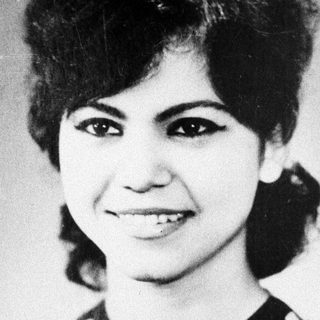 Black and white portrait of a smiling woman in a polka dot top.