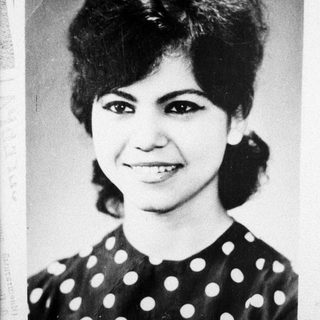 Black and white portrait of a smiling woman in a polka dot top.