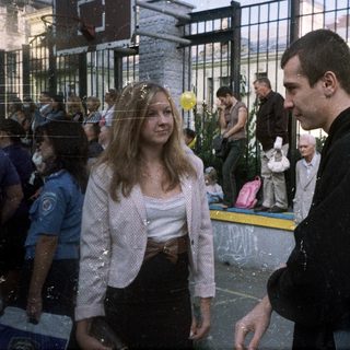Couple stands near a crowd, observing an event.