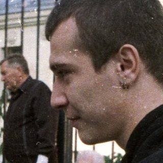 Couple stands near a crowd, observing an event.