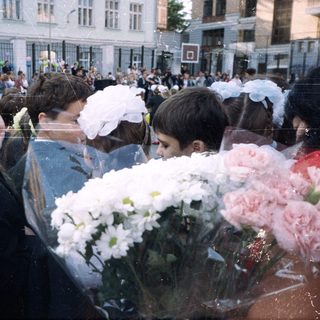 Group of children in formal wear with flowers outside.