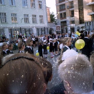 Group of children in uniform gathered outdoors with balloons.