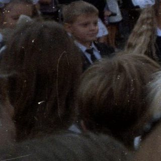 Group of children in uniform gathered outdoors with balloons.