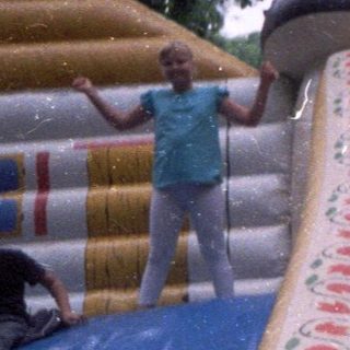 Kids on a colorful, inflatable slide in a park.