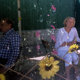 Woman sits at table outside a food stall.