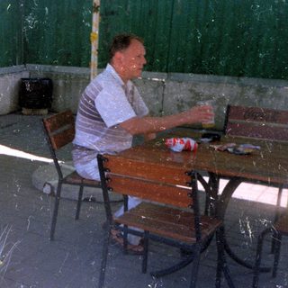Man and child seated at a table outdoors.