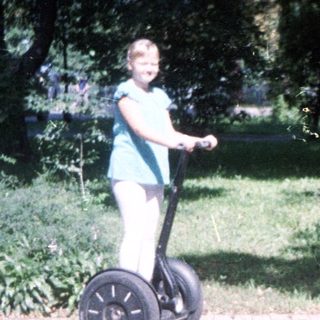 Person rides a Segway in a park setting.