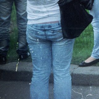 Girl stands near an elaborately decorated monument, people observing.
