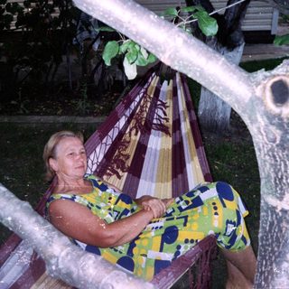 Woman relaxes in a hammock between two trees.