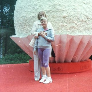 Girl and woman pose in front of a large confectionery display.