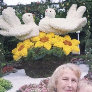 Woman and child near a flower display in a garden.