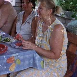 Group enjoying a meal together under a leafy pergola.