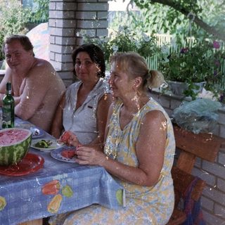 Group enjoying a meal together under a leafy pergola.