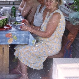Family gathers for a meal on a shaded patio.