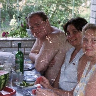 Family gathers for a meal on a shaded patio.
