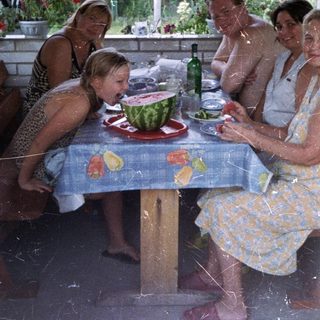 Family gathers for a meal on a shaded patio.