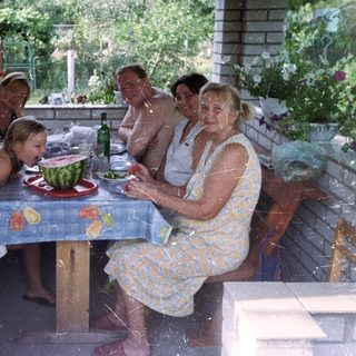 Family gathers for a meal on a shaded patio.