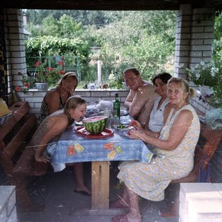 Family gathers for a meal on a shaded patio.