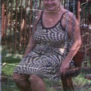 Two women on swings in a grassy backyard.