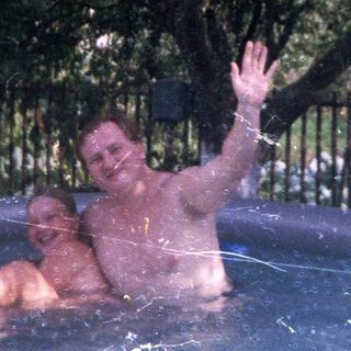 Two men relax in an inflatable pool outdoors.