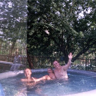 Two men relax in an inflatable pool outdoors.