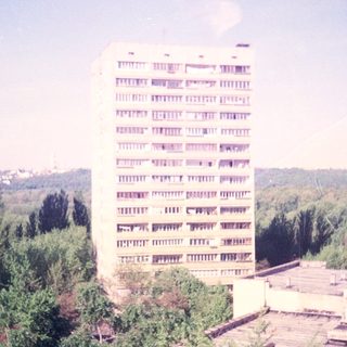 High-rise building overlooks greenery and a distant cityscape.