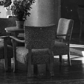 Black and white photo of a room with furniture and bust.
