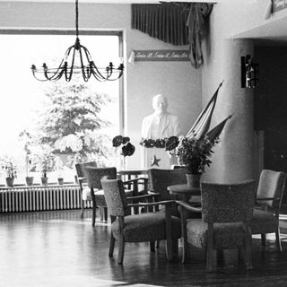 Black and white photo of a room with furniture and bust.