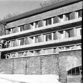 Here's a brief summary of the image: Multistory brick building with balconies, snow-covered landscape.