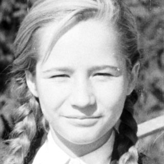 Here's a brief summary of the image: Black and white portrait of a young girl with braided hair.