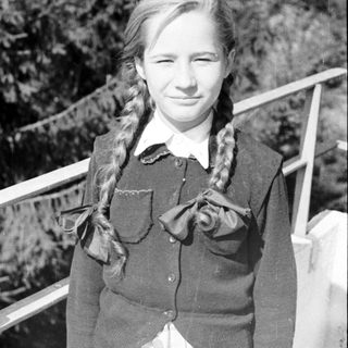 Here's a brief summary of the image: Black and white portrait of a young girl with braided hair.